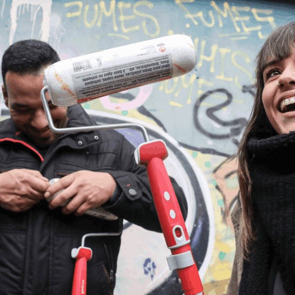 Imagen que muestra una acción de intervención comunitaria llevada a cabo por Emaús. En la fotografia se ve una chica y un chico con un rodete de pintura delante de un muro con grafittis