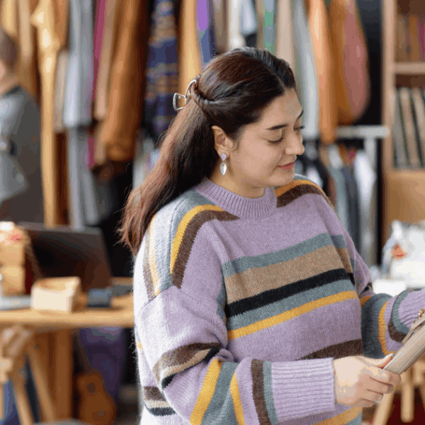 Dona revisant roba en un taller de reutilització tèxtil, representant projectes d’economia circular i inserció sociolaboral per a persones en situació vulnerable
