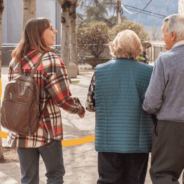 Imatge de dues persones grans beneficiàries del programa Vincles, passejant amb una activadora comunitària en un poble dels Pirineus.
