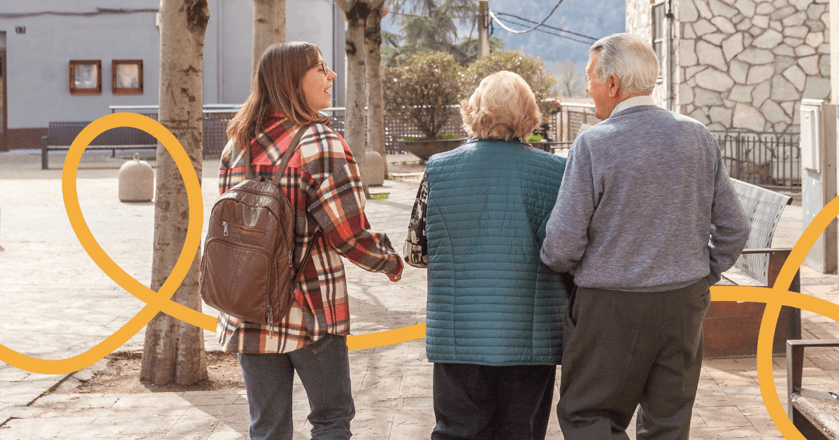 Imatge de dues persones grans beneficiàries del programa Vincles, passejant amb una activadora comunitària en un poble dels Pirineus.